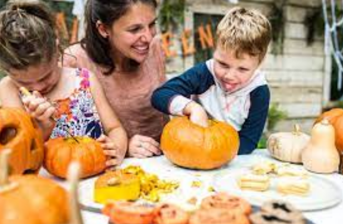 A mother and two boys make lanterns out of pumpkins for Halloween