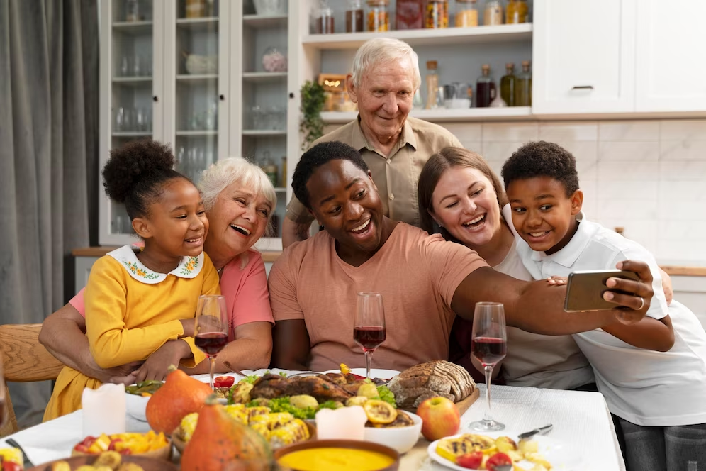 Image of a family gathered around a dining table, capturing a selfie photo together.