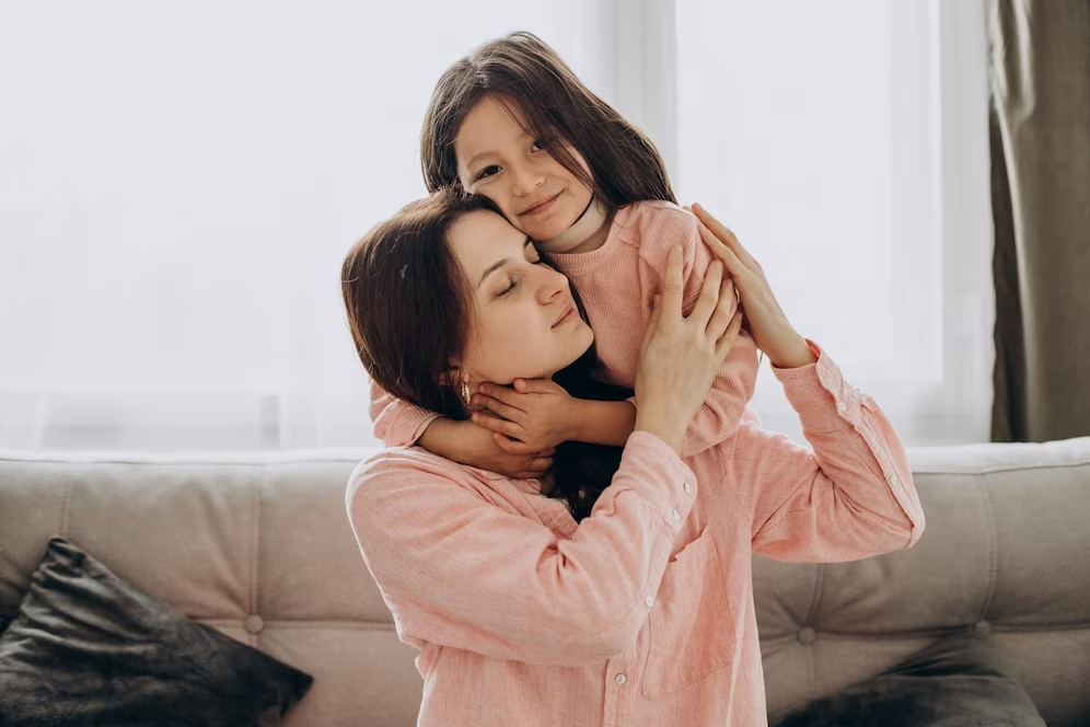 Image of a mother and daughter wearing pink, embracing each other in a heartfelt hug.