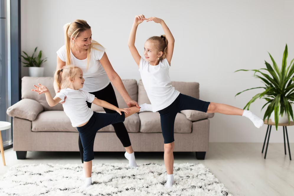 Image of two kids and one woman practicing indoor yoga on a carpet.