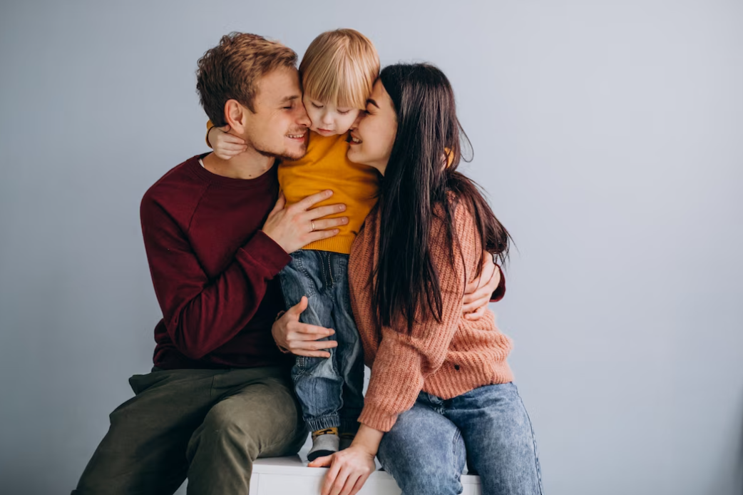 Mother and father with little son together on grey background