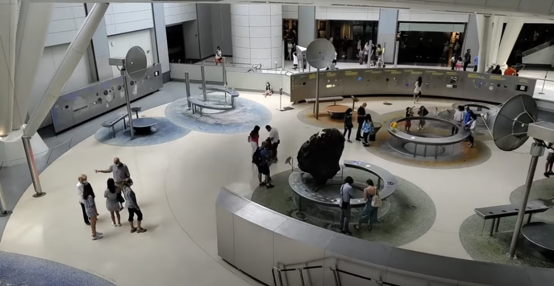 Top view of a museum with people walking around and various displayed items.