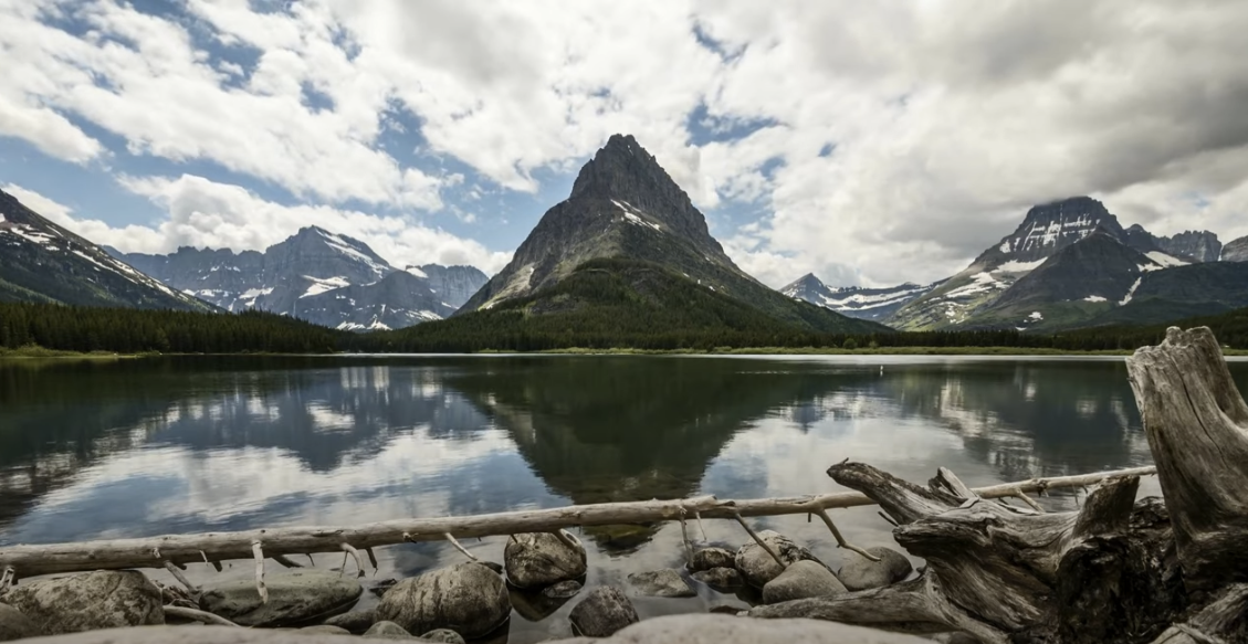 Scenic view of a majestic mountain, serene lake, and expansive sky.