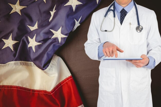 Doctor holding a tablet against the background of the American flag