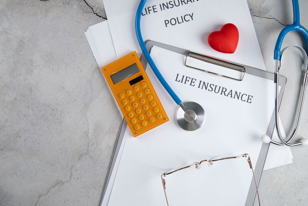 calculator, stethoscope, heart, glasses, and sheets with life insurance on it